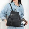 Black concealed‑carry backpack worn by a model, with the concealed‑carry compartment opened to reveal the reinforced holster area.