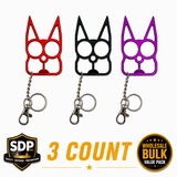 Three cat‑shaped self‑defense keychains in assorted colors displayed together, showing the pointed ear impact tips and dual finger‑grip eye holes.