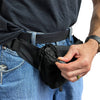 Black concealed‑carry fanny pack worn on the waist, displaying its compact profile and accessible front zipper.