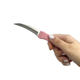 Curved pink comb‑style knife held in hand, showing the concealed blade integrated into the comb design.