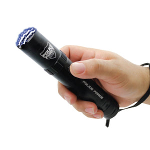Black Police Force tactical stun flashlight held in a person’s hand, showing its textured grip and front electrode area.