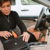 Trigger‑grip SABRE Aim & Fire pepper gel positioned in a purse compartment, highlighting accessibility and compact design.