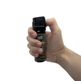 Three‑ounce Streetwise 18 stream pepper spray held in hand, highlighting the flip‑top actuator and compact canister design.