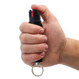 Streetwise 18 stream pepper spray (0.75‑oz) shown in hand with the key ring and clip visible to illustrate size and grip.