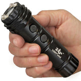 Hand holding the ZAP Light Mini stun gun flashlight, showing the compact body and front light lens.